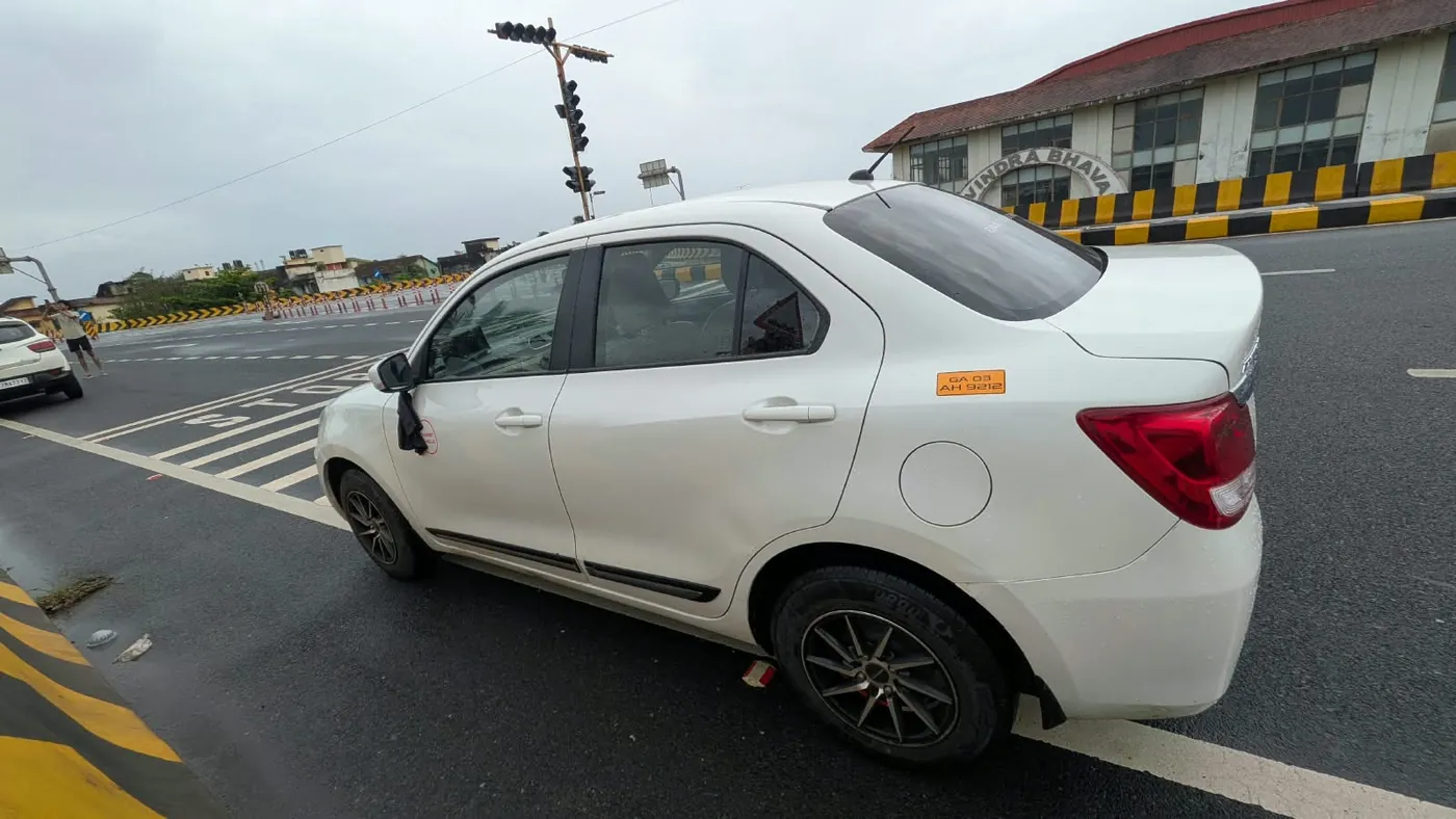 White Maruti Suzuki Dzire sedan taxi on a Goa road