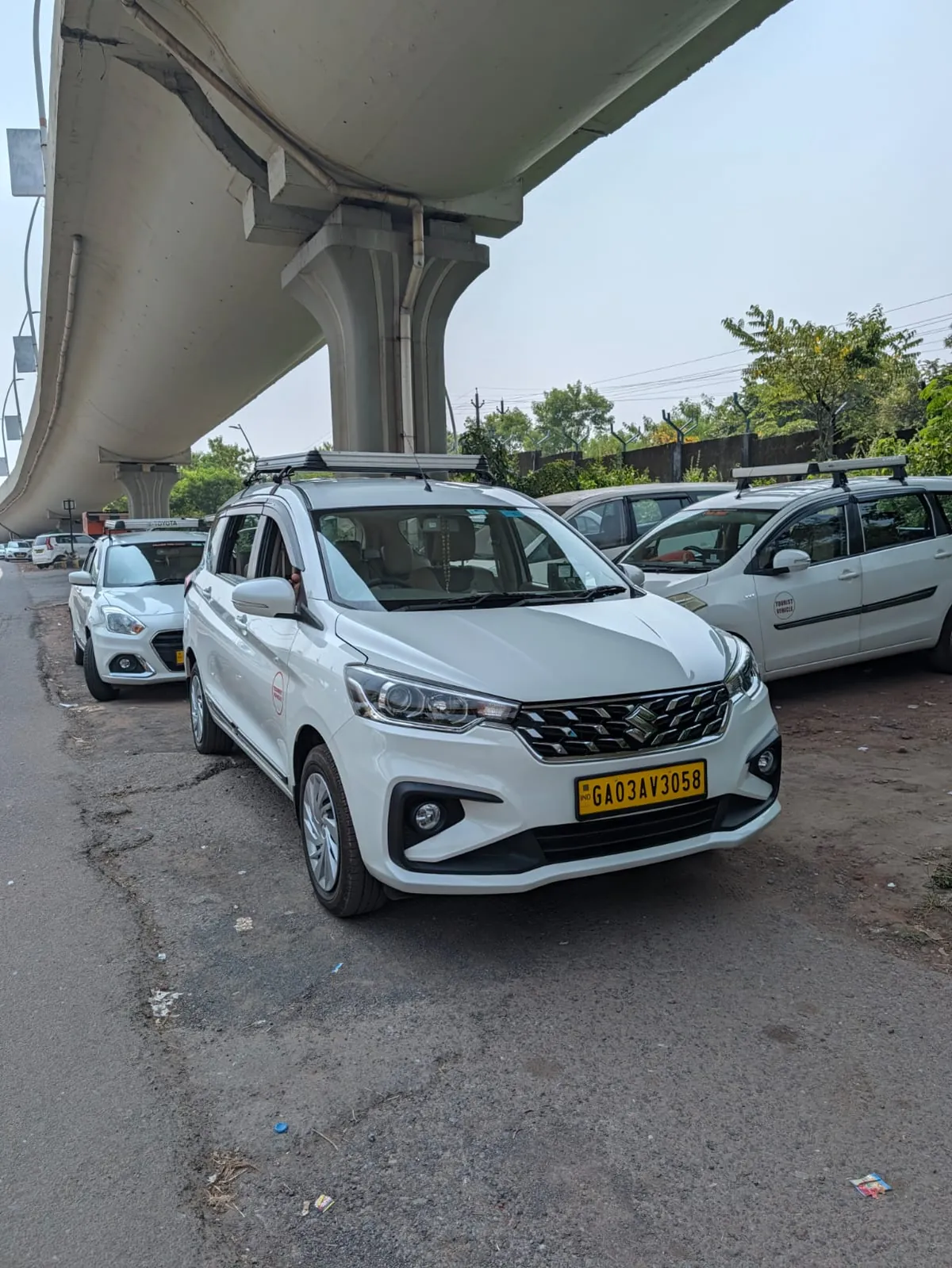 White Maruti Suzuki Ertiga taxi with roof carrier parked near Dabolim Airport