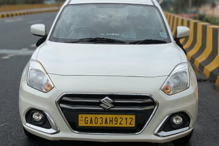 White Maruti Suzuki Dzire sedan taxi on a Goa highway