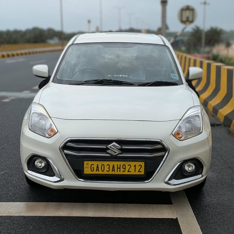 White Maruti Suzuki Dzire sedan taxi on a Goa highway