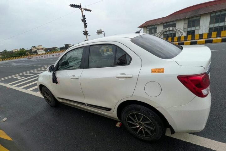 Side view of the white Maruti Suzuki Dzire taxi on a Goa road